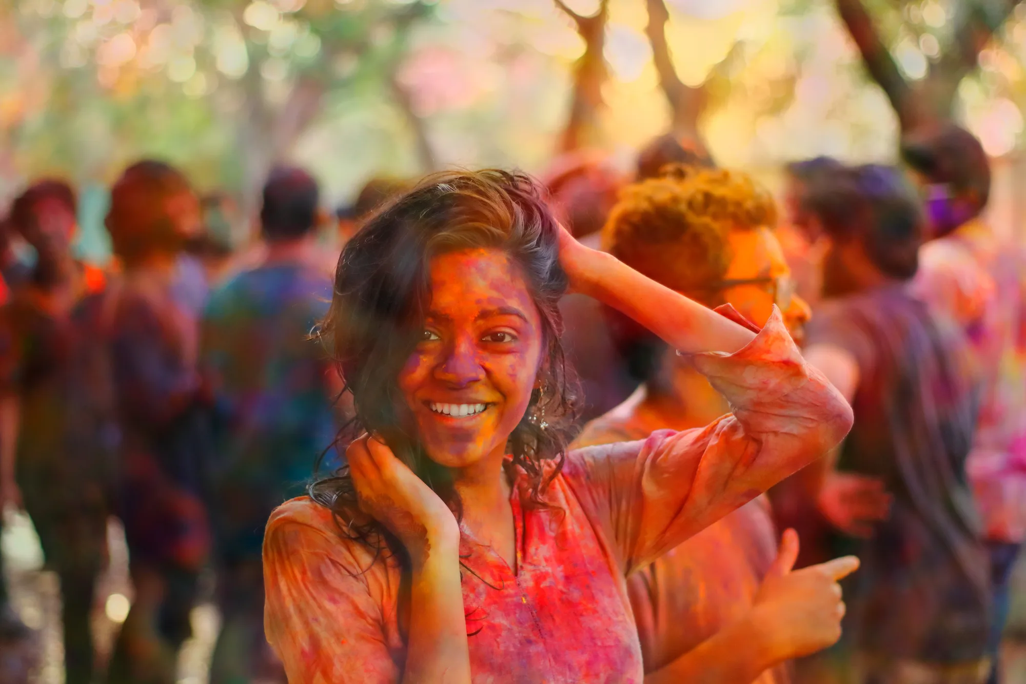 A young woman laughing at Holi, her face covered in colour.